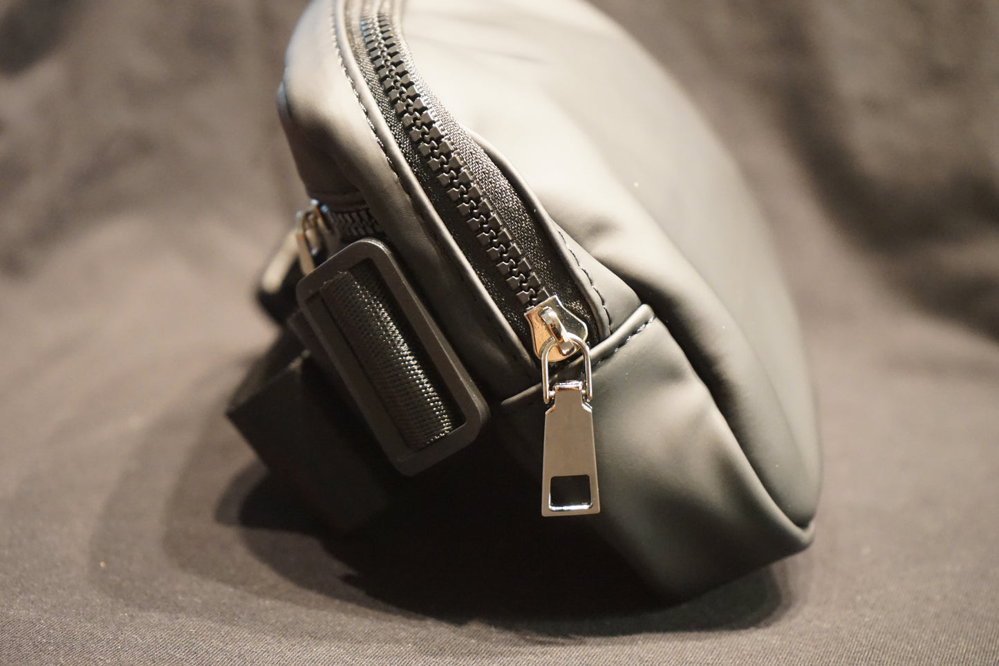 Close-up of a trident fanny pack with a zipper on a textured surface
