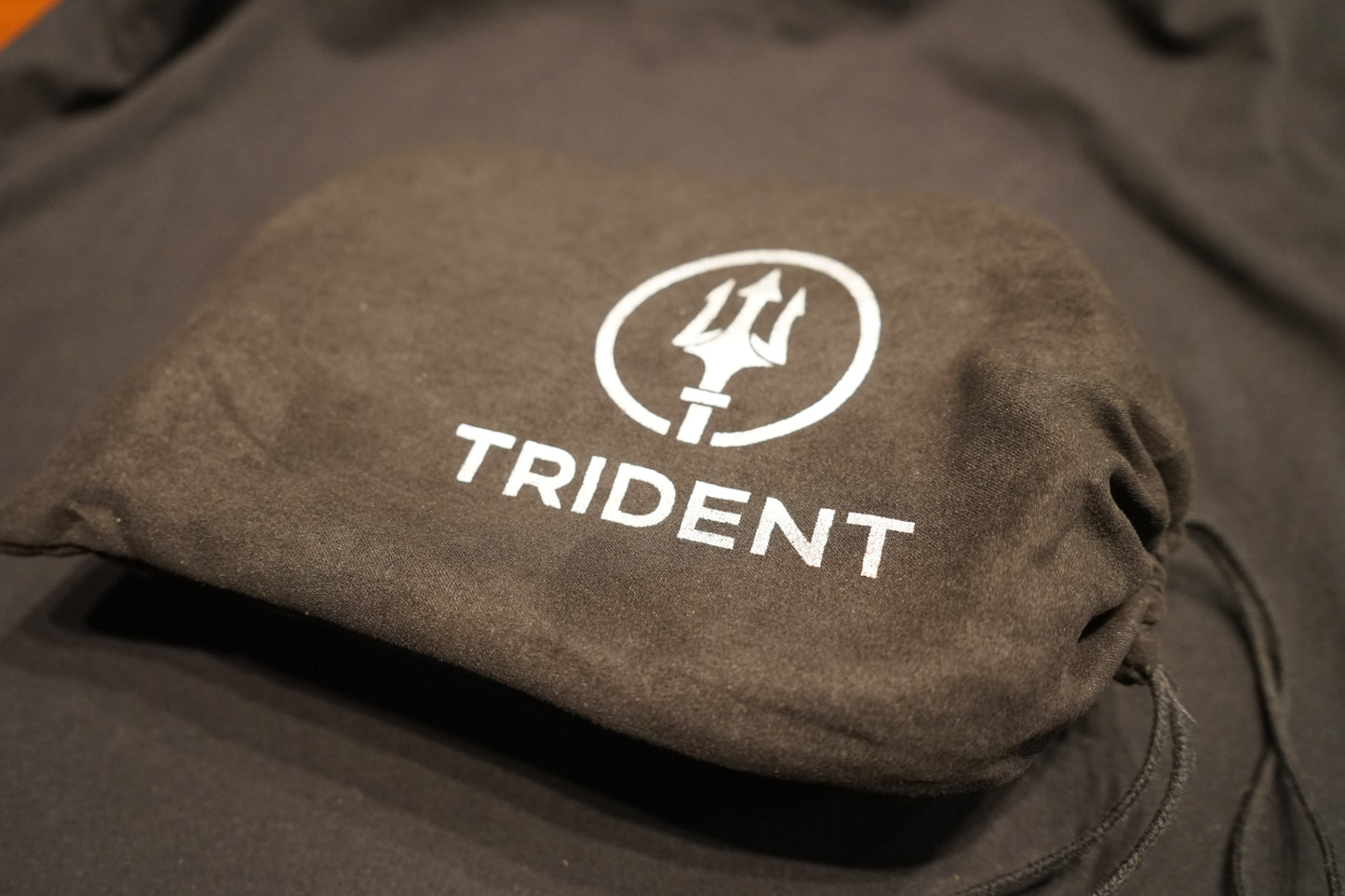Brown pouch with Trident logo on a dark background